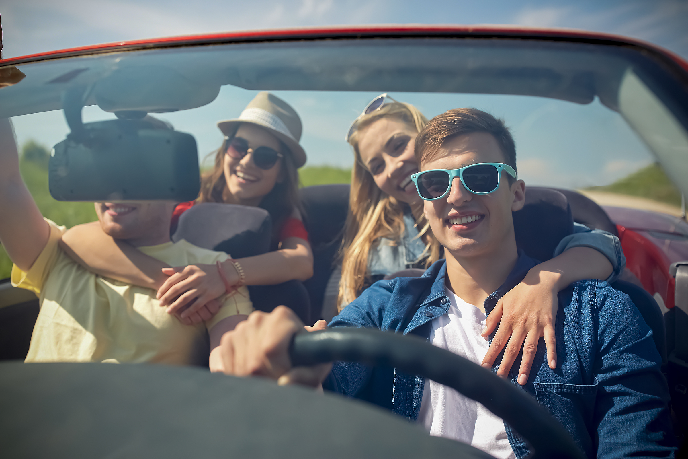 Junge Menschen fahren gut gelaunt in einem Cabrio